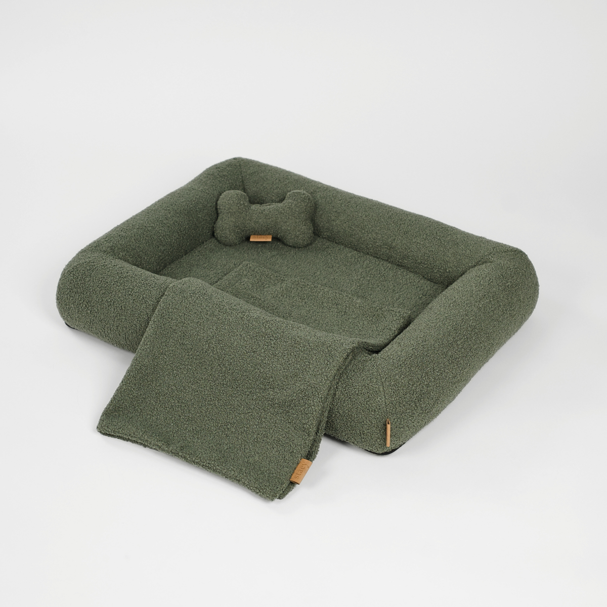 Hundkorgen i Moss Green bouclé med en benformad kudde och en matchande matta