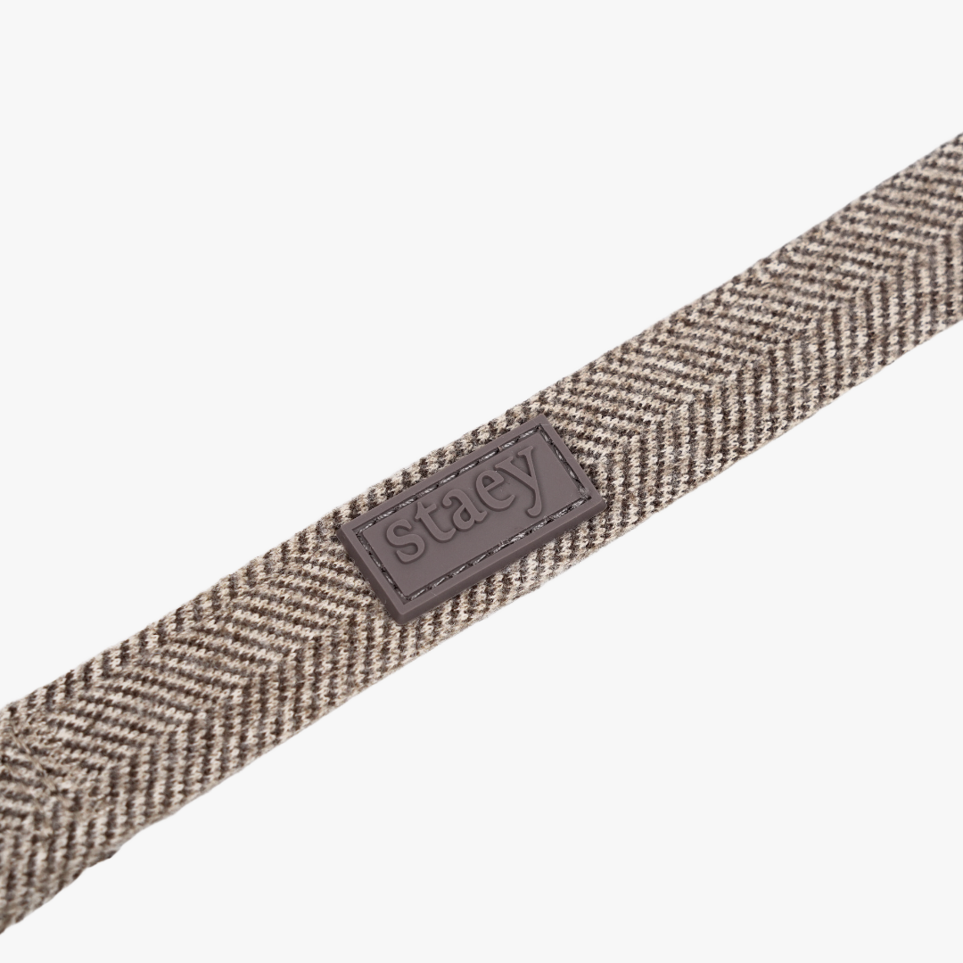 Närbild på mocca-färgat vävt band i Herringbone-mönster och Staey-etiketten